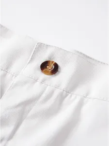 Detailansicht der weißen Freizeitshorts mit strukturiertem Stoff und braunem Knopf