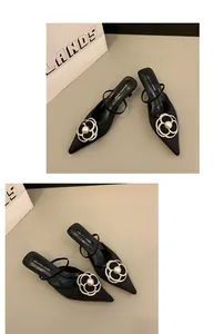 Gros plan sur mules à petit talon noires style français avec fleur de camélia