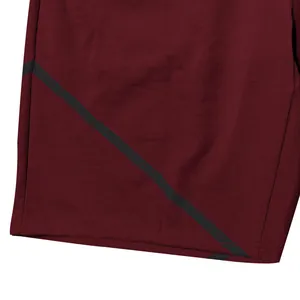 Close-up of burgundy athletic shorts with black diagonal stripe and fabric texture.