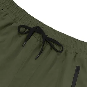 Close-up of olive green athletic shorts with elastic waistband and black drawstring detail