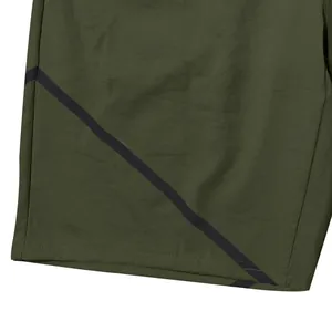 Close-up of olive green men's athletic shorts featuring a black diagonal stripe design