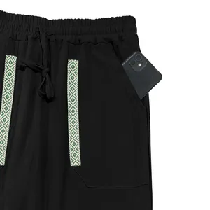 Close-up of black linen trousers pocket with decorative bohemian pattern trim