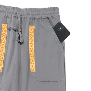 Detailed view showing large pocket capacity of men's gray linen pants with ethnic trim