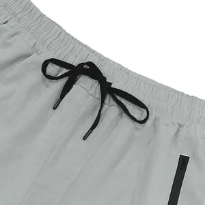 Close-up of elastic waistband with black drawstring and zipper pocket on gray shorts