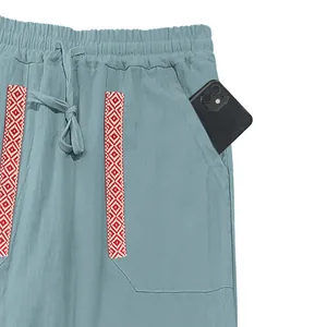 Close-up detail showing the deep side pocket and embroidery on blue linen pants