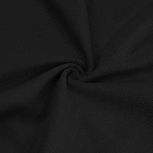 Macro view of black waffle knit fabric showing detailed texture for men's polo shirt.