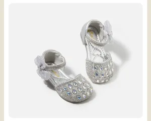Dettaglio di sandali da principessa in cristallo argento per bambina con fiocco luccicante.
