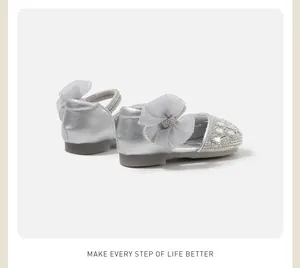 Dettaglio delle scarpe argentate da neonata con strass e fiocco in tulle