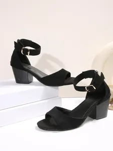 Detailansicht eleganter schwarzer Wildleder-Sandalen mit verstellbaren Gold-Schnallen.