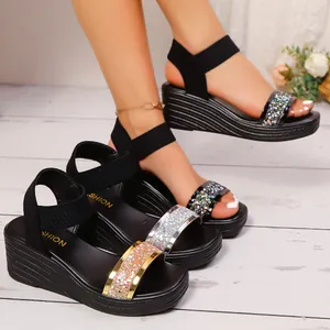 Detailansicht von Damen-Keilplateausandalen mit Glitzerriemen und elastischen Knöchelbändern.