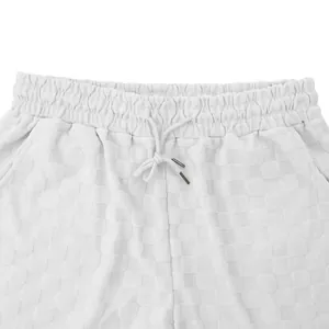 Detalle de pantalones cortos blancos para hombre con jacquard de cuadros y cordón