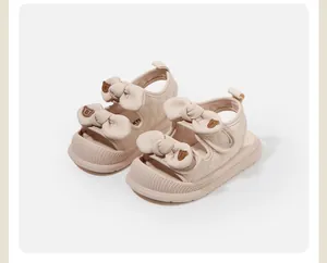Dettaglio di sandali beige per bambine con doppio fiocco e orsetti