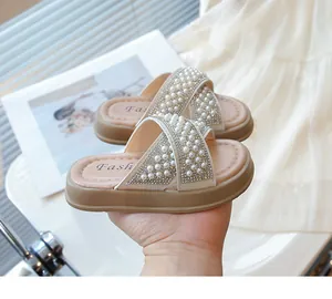 Primer plano de sandalias para niñas con perlas y pedrería en color beige