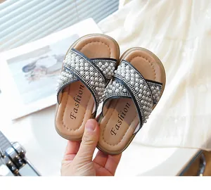 Primer plano de elegantes zapatillas de verano para niña con perlas y correas cruzadas
