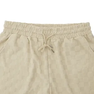 Primer plano de pantalones cortos de hombre en jacquard a cuadros beige con cordón.