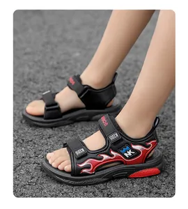 Primer plano de sandalias negras para niños con patrones de llamas rojas y velcro.