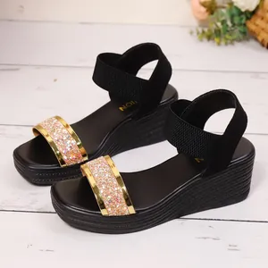 Detailansicht der schwarzen Keilsandalen mit schimmernden Paillettenriemen und Gummibändern.