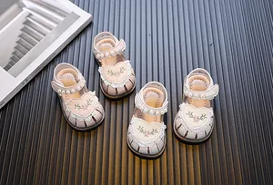 Close-up detail of cream toddler girl sandals with embroidered hearts and pearls.
