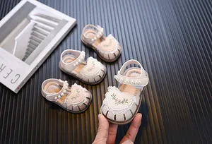 Macro view of baby girl princess sandals with pearl strap and embroidered heart design