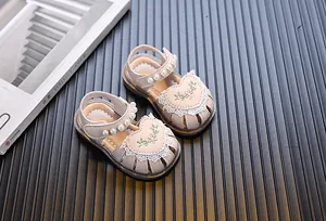 Detailed view of pink toddler sandals with embroidered heart patches and pearl straps