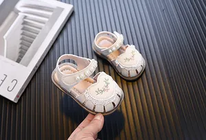 Close-up view of elegant baby girl sandals with pearl straps and floral embroidery details