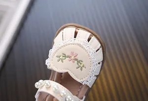Close-up of baby girl princess sandals featuring pearl strap and floral embroidery