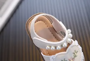 Detailed close-up of toddler girls' princess sandals with pearls and floral embroidery