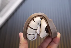 Close-up showing the flexible and soft rubber sole of cream baby girls walking sandals