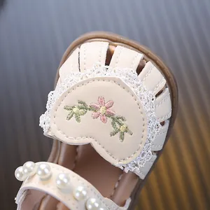 Close-up of baby girl sandals with pearl accents and floral heart embroidery detail