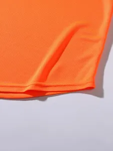 Gros plan sur le tissu en maille orange respirant et l'ourlet piqué de la veste de sport