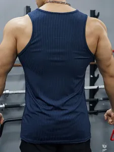 Back view detail of navy blue ribbed slim fit fitness tank top on male model in gym