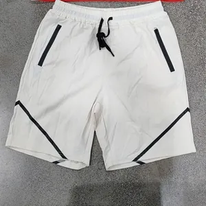 Detailansicht der weißen Sportshorts mit schwarzen Reißverschlüssen und Streifen.