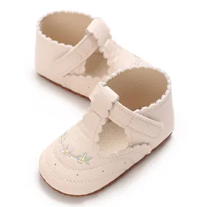 Detail van crèmekleurige baby loopschoentjes met bloemmotief en geschulpte randjes