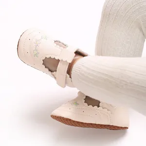 Detailopname van babyschoenen voor meisjes met bloemenprint en zachte zolen.