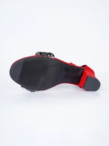Close-up detail view of the non-slip black sole and chunky heel on red rhinestone sandals