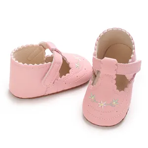 Detail van roze baby prinsessenschoenen met geborduurde bloemen en geschulpte randen.