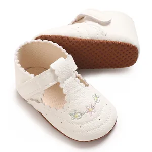 Detail van het bloemmotief op witte loopschoentjes voor baby meisjes.