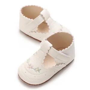 Gedetailleerd overzicht van witte baby meisje wandelschoenen met bloemen borduurwerk en zachte zool.