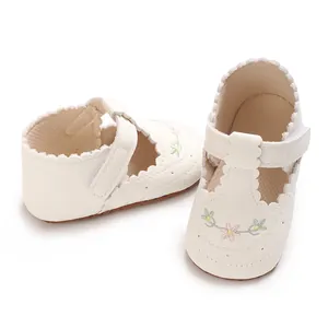 Gedetailleerde close-up van witte baby loopschoentjes met verfijnd geborduurde bloemen