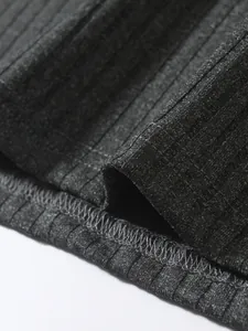 Macro detail of charcoal gray ribbed knit fabric and hem stitching on a men's vest.