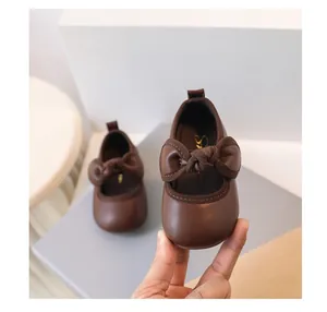 Close-up of brown baby princess shoes featuring a decorative bow and soft leather texture