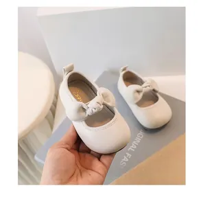 Close-up of white baby girl princess shoes with soft soles and decorative bows