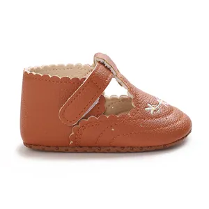 Zijaanzicht van bruine babyschoen voor meisjes met bloemborduursel en geschulpte rand.