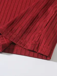 Detailed close-up of red ribbed fabric texture and hem stitching on men's tank top