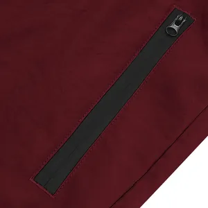 Dettaglio macro della tasca con cerniera nera impermeabile sui pantaloncini rossi da uomo