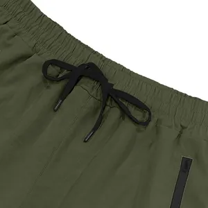 Dettaglio pantaloncini uomo verde oliva ad asciugatura rapida con coulisse e tasca zip.