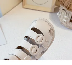 Close-up detail of beige toddler girl Roman sandals with soft leather straps and circular buckles