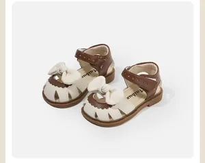 Detailed view of toddler girls' cream and brown walking sandals with decorative bow