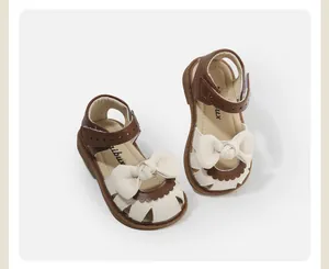 Detailed view of cream and brown toddler girl sandals with a decorative large bow