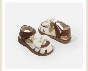 Detail of cream and brown baby girl closed-toe sandals with a bow accent